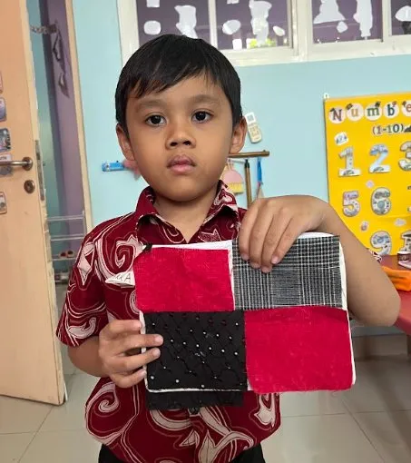 Seorang siswa Playgroup menunjukkan kain batik tie-dye
