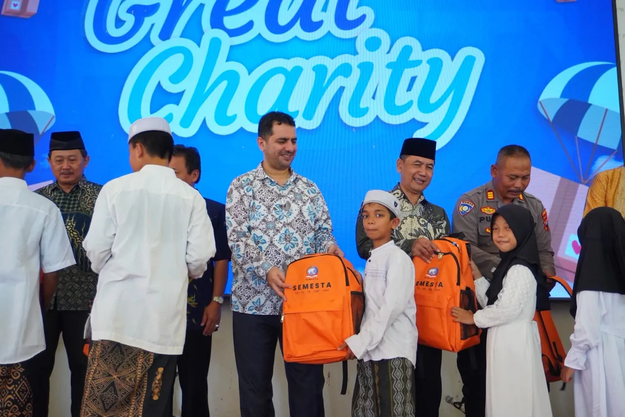 Seorang tamu menyerahkan tas ransel oranye Semesta kepada seorang anak di atas panggung